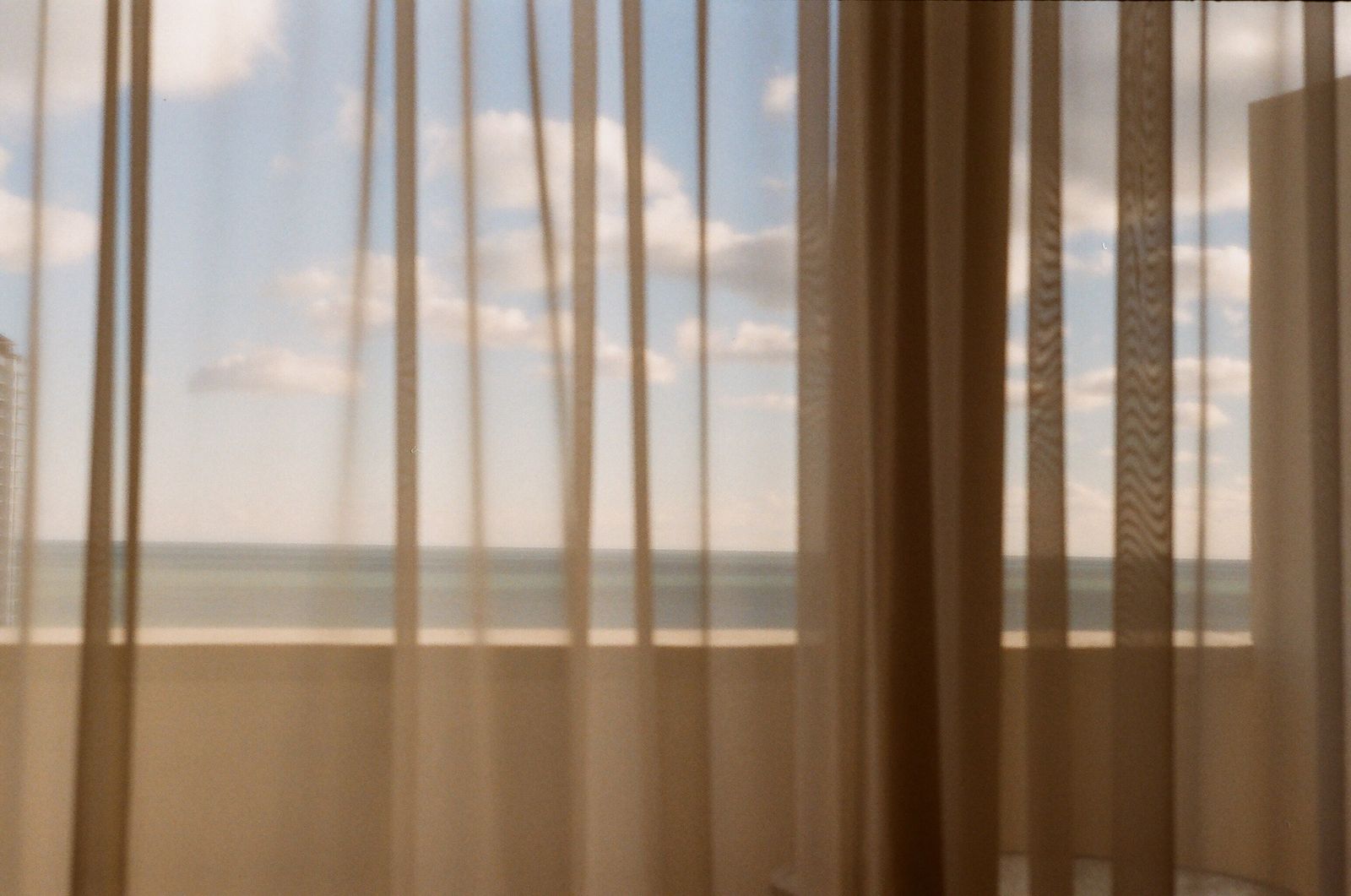 Cortinas transparentes frente a un ventanal con el mar y el cielo detrás