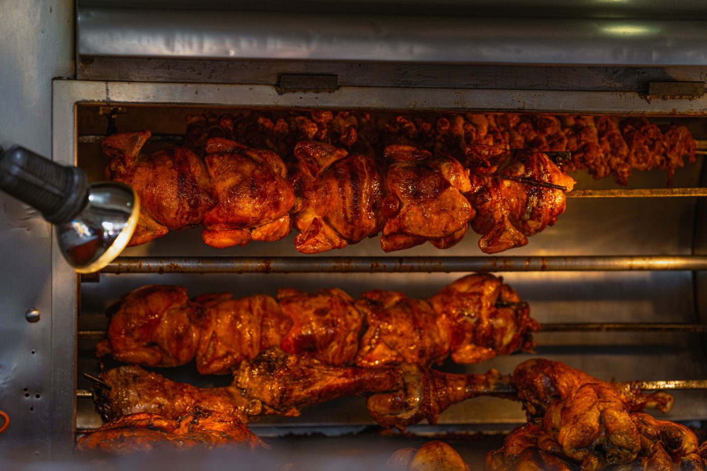 Pollos dorándose en el horno giratorio, en tres filas de espetos