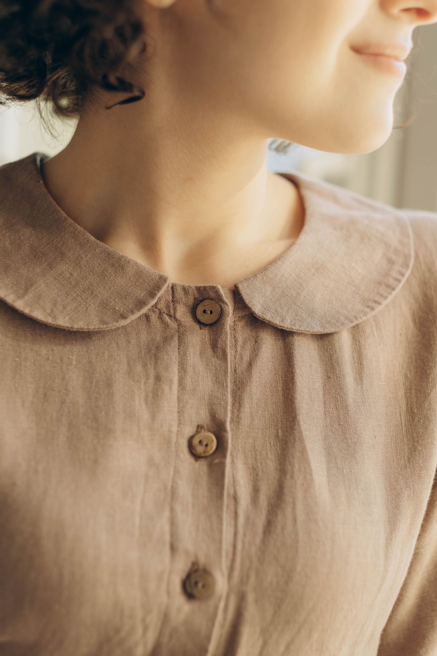 Detalle del cuello bebé y los botones de coco del vestido de lino color tierra